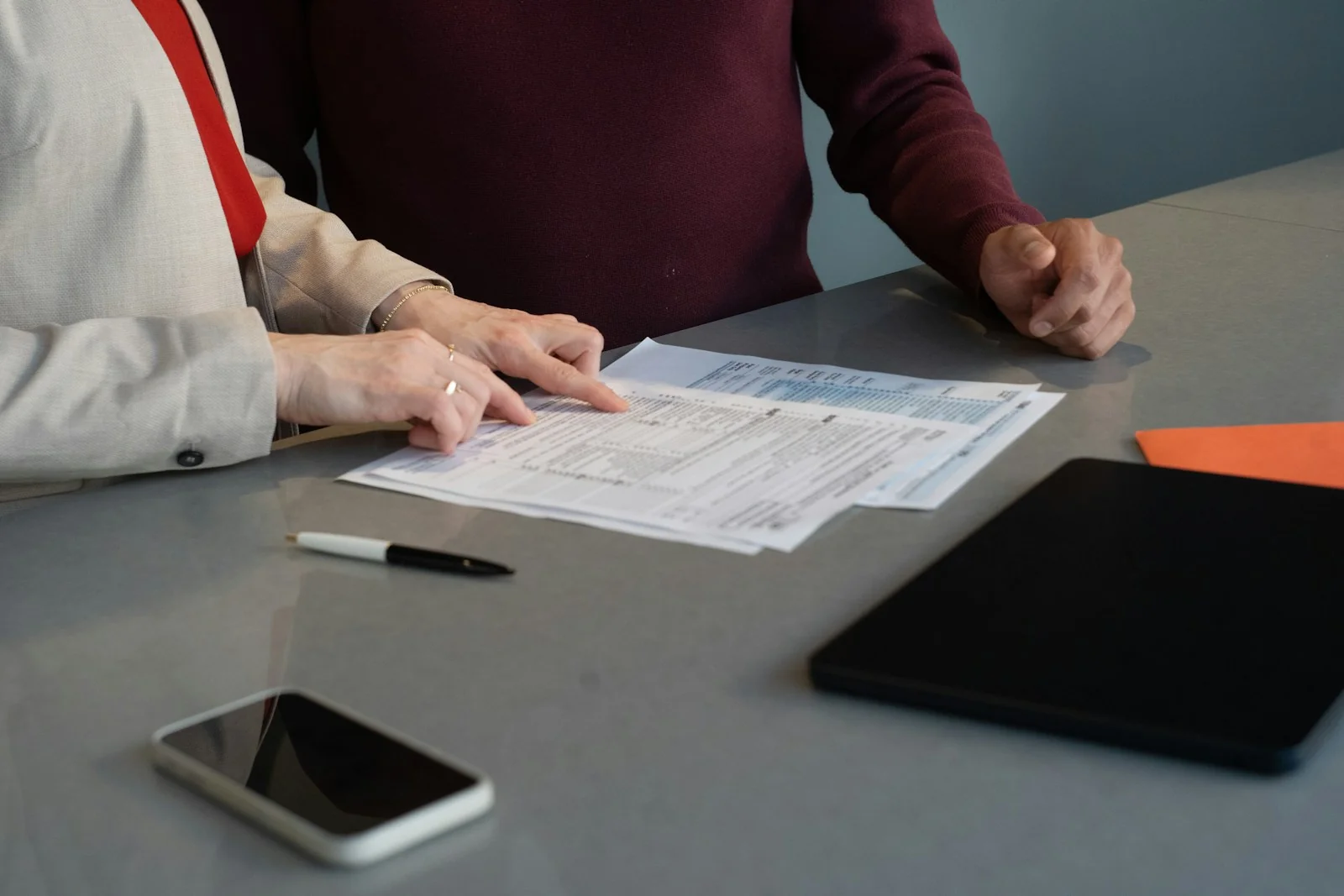 Deux personnes examinent ensemble un document à une table de travail